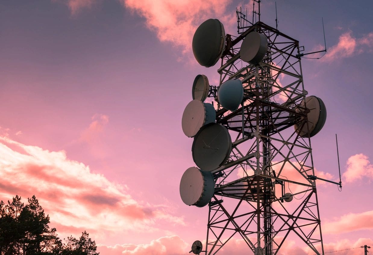 A tall tower with many satellite dishes on top of it.